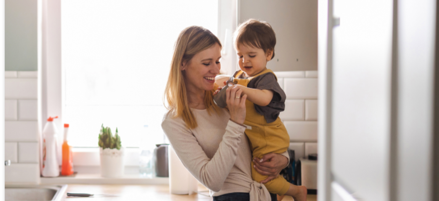 Woman holding toddler in kitchen